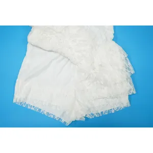 Vista dettagliata del pizzo floreale bianco e dell'orlo a balze di una tutina sexy