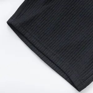 Close-up of black ribbed fabric texture and hem stitching detail on casual beach shorts.
