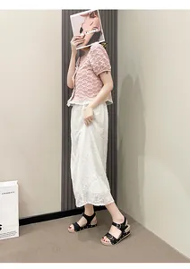 Sandales plates noires décontractées à boucles dorées portées par un mannequin chic