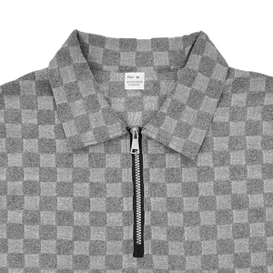 Close-up detail of grey checkerboard jacquard polo shirt with half-zip collar