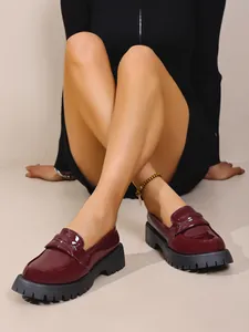 Λεπτομερής προβολή των μπορντό λουστρίνι loafers με χοντρή σόλα σε βρετανικό vintage στυλ.