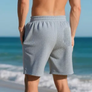 Back view of men's grey jacquard beach shorts with elastic waist on a sunny beach