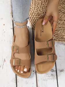 Close-up of brown platform buckle sandals with soft textured straps and vintage bronze buckles.