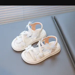 Détail de sandales blanches pour filles avec ailes de papillon et strass étincelants.
