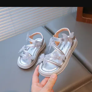 Détail rapproché de sandales argentées pour filles avec ornements papillons en strass