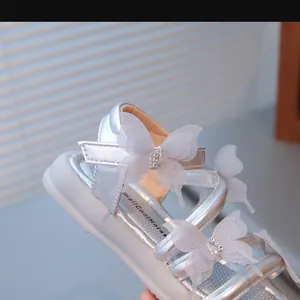 Gros plan de sandales argentées pour filles avec papillons 3D et strass brillants