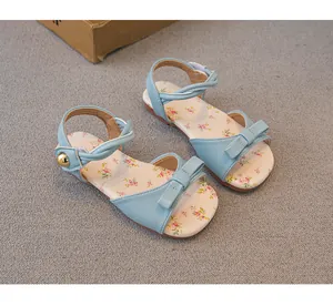 Close-up of baby girl blue summer sandals featuring floral insoles and cute ribbon bows