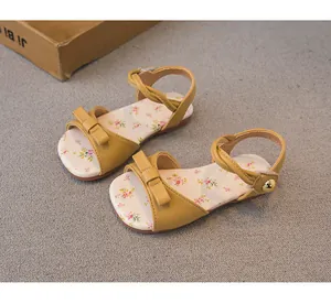Close-up of yellow girls' bow sandals featuring a delicate floral print on the insole.
