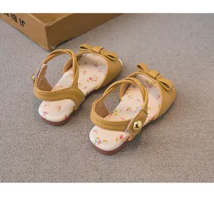 Detailed view of yellow toddler sandals with floral pattern insole and bow knot decoration