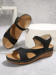 Dettaglio di sandali con zeppa neri da donna con chiusura a velcro e cuciture bianche
