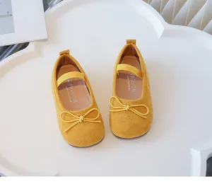 Detailed top view of yellow children's suede flats with bow and elastic strap