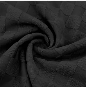 Close-up detail of heavy checkerboard jacquard fabric on black men's polo shirt.