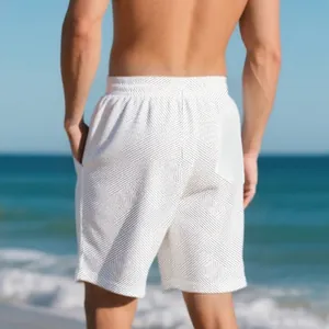 Detail view of men's loose heavy jacquard textured shorts in a beach setting.