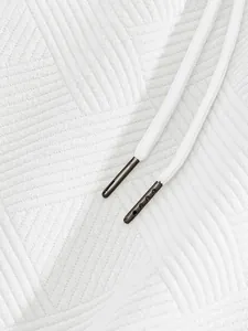 Close-up of white jacquard texture fabric and drawstring aglets on men's shorts.