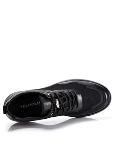 Detail van bovenaf: lichte herensneaker van zwart leer en ademend mesh materiaal.
