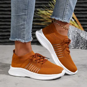 Nahaufnahme stilvoller ingwerfarbener Strick-Sneaker mit weißer Plateausohle am Bein