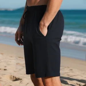 Close-up detail of black men's summer shorts showing heavy jacquard texture on beach