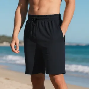 Close-up detail of black men's summer shorts with jacquard texture shown on a sunny beach