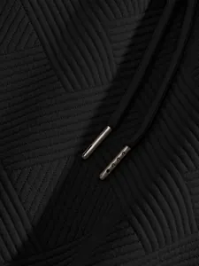Macro view of heavy jacquard fabric and metal drawstring tips of black men's shorts.