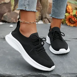 Stylische schwarze Flyknit-Sneaker mit weißer Plateausohle, am Fuß draußen gezeigt.