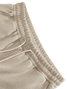 Detailed macro view of the textured jacquard fabric on beige men's drawstring shorts.