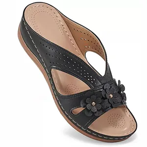 Detailed view of black wedge sandals featuring decorative 3D flowers and cutout straps.