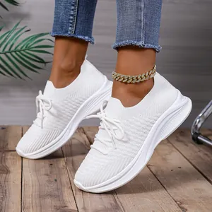 Modische weiße Damen-Sneaker aus Fluggewebe mit Plateausohle auf einem Holzfußboden.