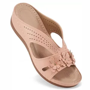 Detailed view of floral cut-out patterns and pearl accents on pink wedge sandals