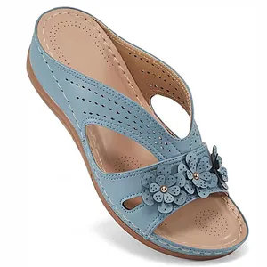 Detail of blue wedge sandal with hollow flower embellishments and laser-cut pattern