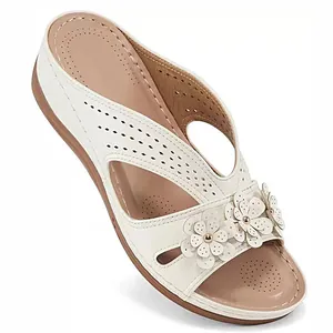 Detailed view of white wedge sandals featuring laser-cut patterns and flower accents