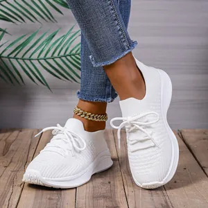 Nahaufnahme stylischer weißer Flyknit-Plattform-Sneaker auf Holzbodendetail mit Denim