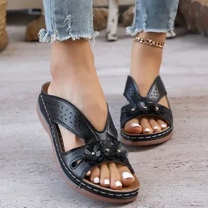 Detailed view of black platform wedge sandals featuring hollow-out patterns and flower accents