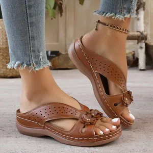 Detailed view of brown wedge sandals featuring hollowed-out patterns and flower accents