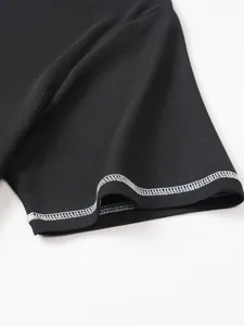 Detail of black seersucker fabric with white contrast stitching on shirt hem.
