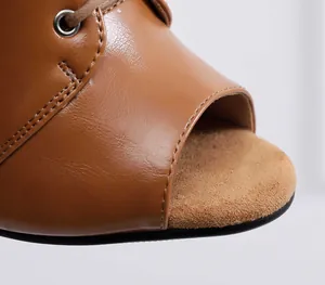 Close-up macro view of brown peep-toe dance heel showing leather texture and metal eyelet