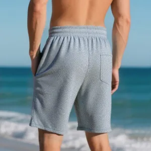 Detailed macro view of men's jacquard texture shorts against a beach background.