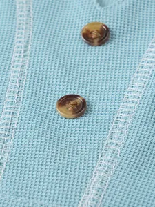 Macro view of textured light blue seersucker fabric and brown buttons on men's summer shirt