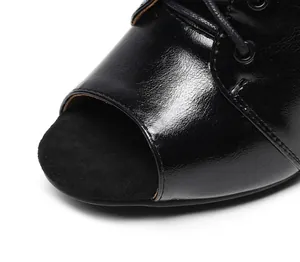 Detailed macro view of black peep-toe dance bootie featuring shiny patent leather material