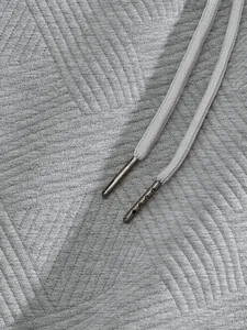 Close-up of grey heavyweight jacquard fabric with textured pattern and drawstring detail