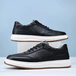 Close-up of men's black perforated leather sneakers with white sole on blue backdrop