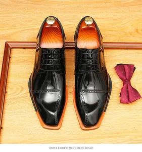 Top view of polished black leather Derby shoes with vibrant orange soles and brogue details