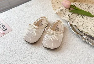 Detalle de los zapatos de princesa para niña en encaje crema con un lazo decorativo delicado