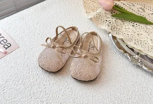Detalle del bordado de encaje y las lentejuelas en los zapatos tipo mule con lazo para niña
