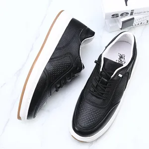 Close-up view of premium black perforated leather slip-on sneakers with durable white soles.
