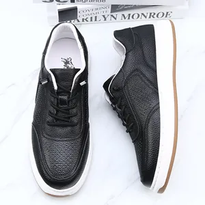 Detail of black perforated leather sneakers for men with lace-free design and white sole.