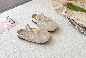 Primer plano detallado de pantuflas de encaje crema para niñas con un lazo elegante