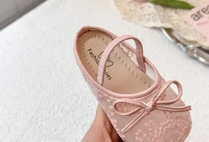 Detalle de zapatos de princesa rosa de encaje para niña con un lazo.
