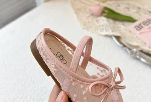 Detalle en primer plano de zapatillas de princesa de malla rosa para niña con lazo.