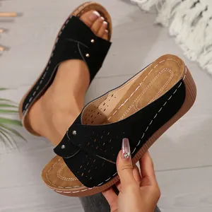 Detailopname van zwarte sleehak sandalen met opengewerkt design en witte stiksels