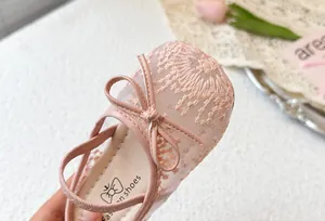Primer plano detallado de zapatos de princesa rosas para niña con malla bordada y un lazo